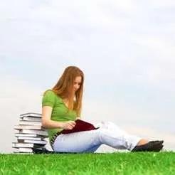 Girl seated at a table, studying or doing homework with a smile