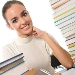Girl smiling while holding a stack of books, symbolising academic success